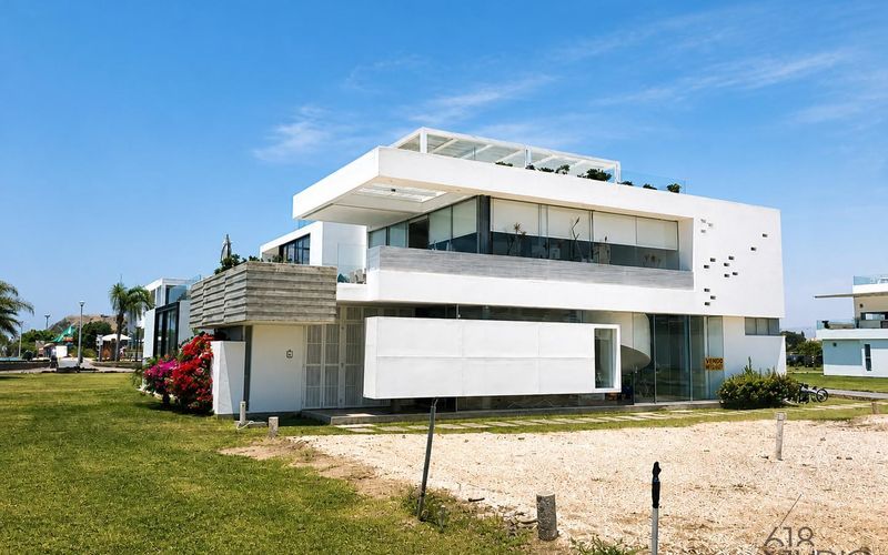 Fachada blanca de dos niveles de la casa de playa en Las Arenas, Asia